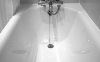 Baignoire blanche avec robinet et tuyau, eau qui coule dans la salle de bain