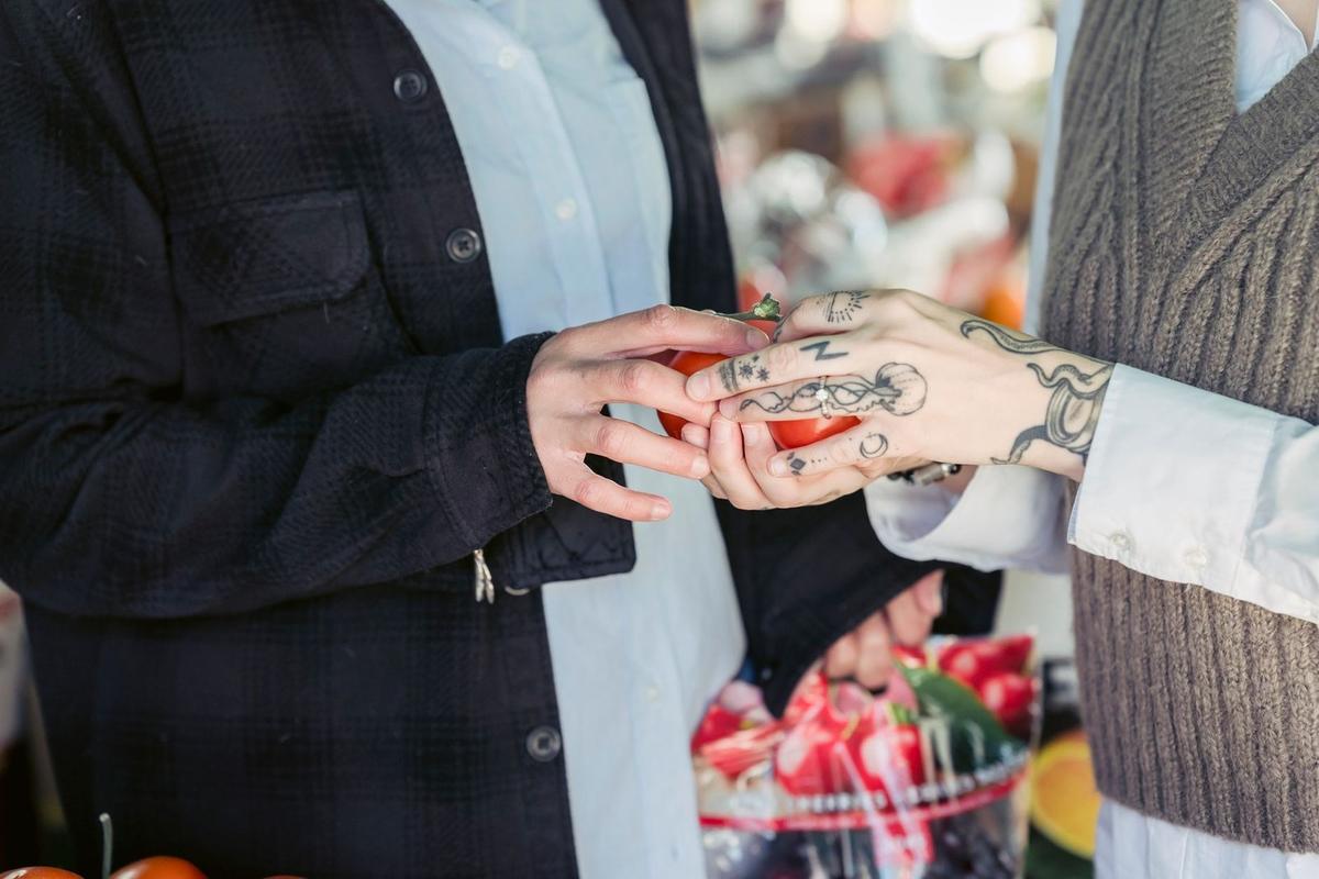 Échange de pomme entre deux personnes tatouées dans un marché Échange de pomme entre deux personnes tatouées dans un marché