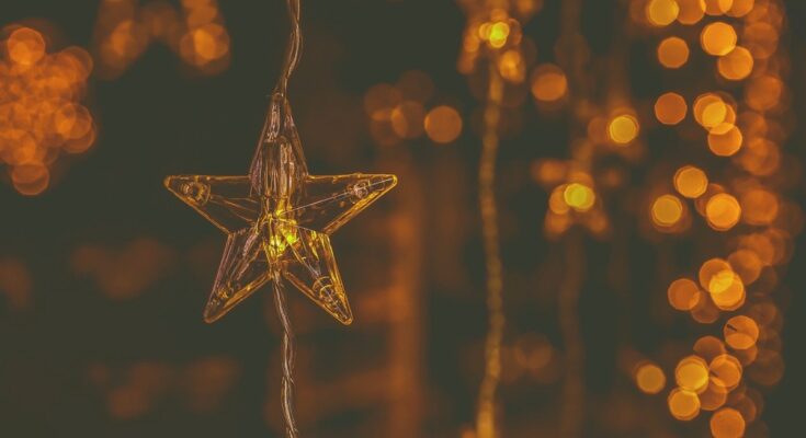 Étoile lumineuse suspendue, fil fin, arrière-plan flou de lumières chaudes