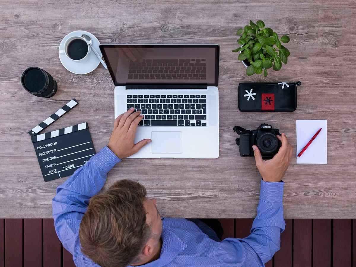 Un homme travaille sur un ordinateur portable, entouré d'accessoires